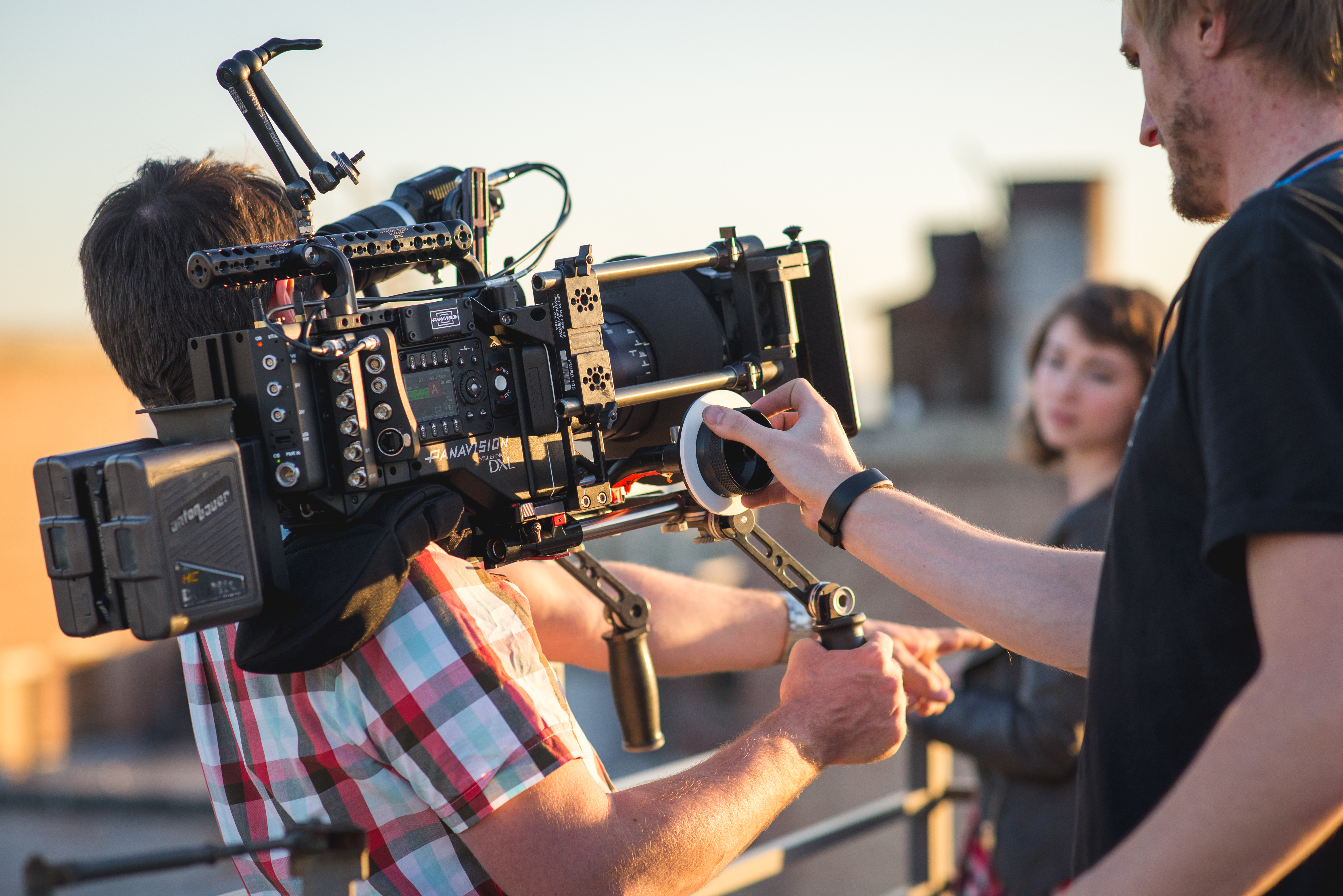 A focus puller adjusting focus on a large cinema lens during a professional film production